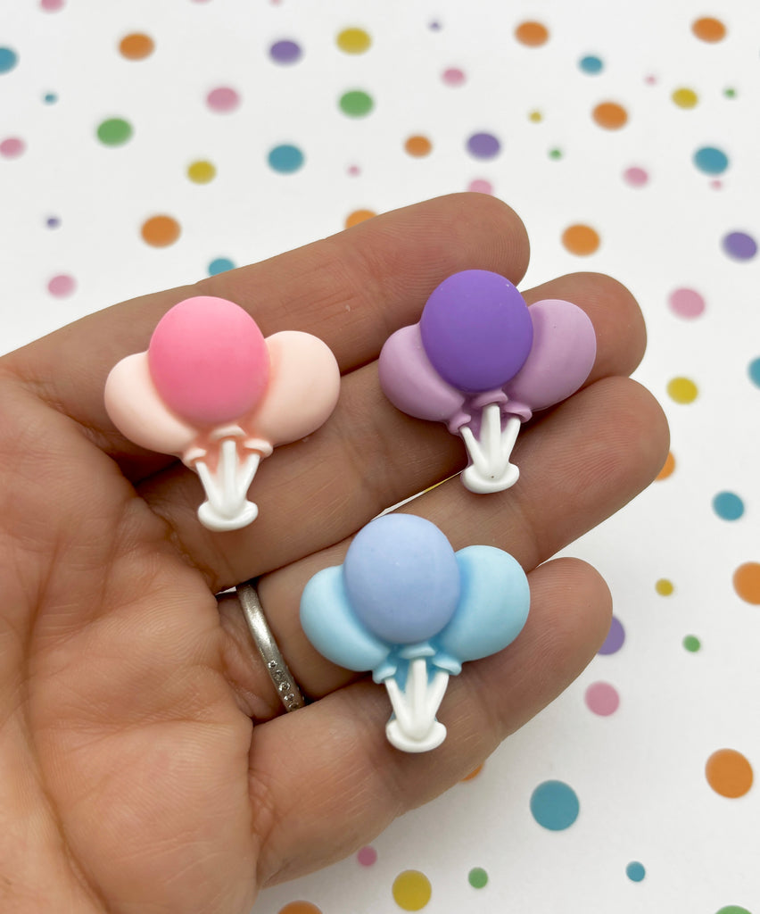 a person holding three small balloons in their hand