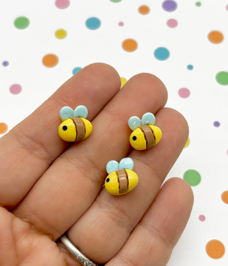 a hand holding a pair of yellow and brown bee earrings