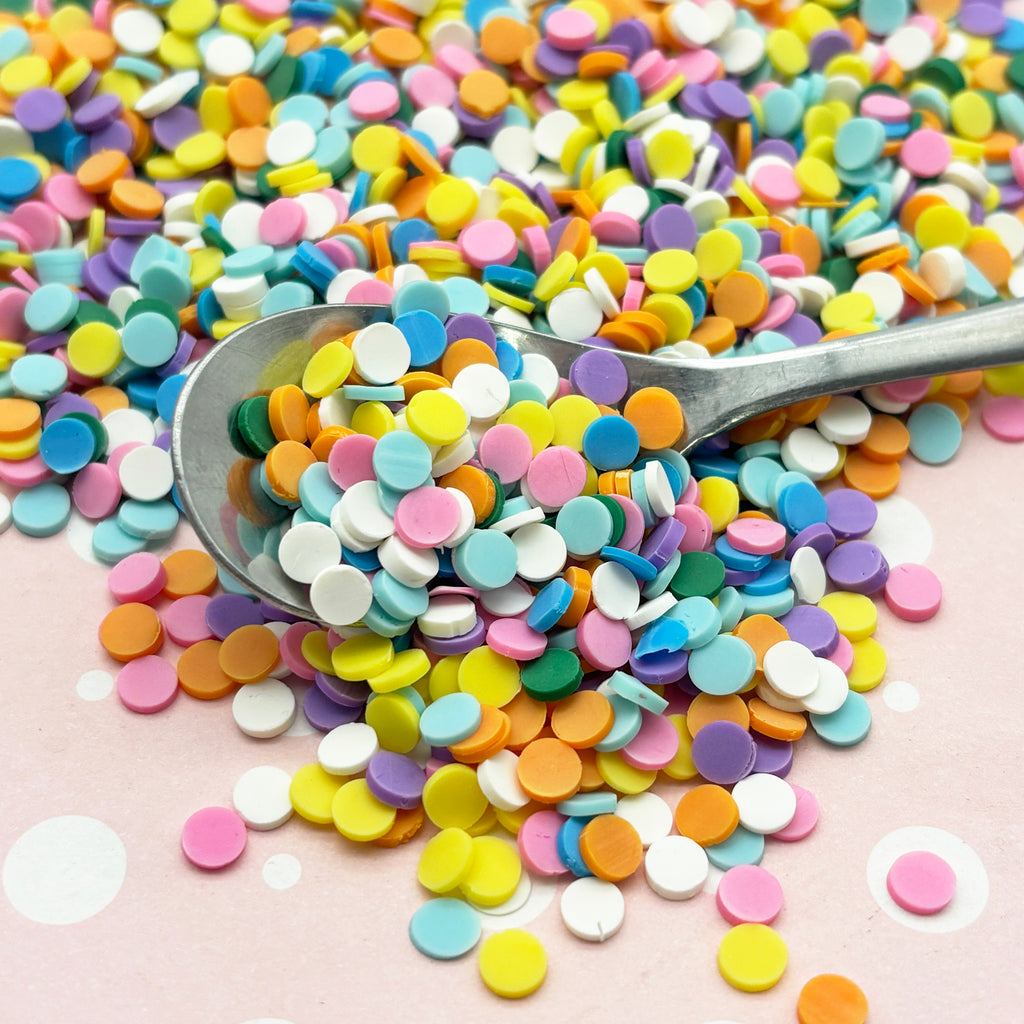 a spoon filled with colorful confetti on top of a table