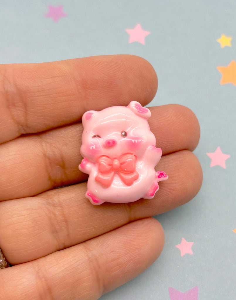 a hand holding a tiny pink bear with a bow