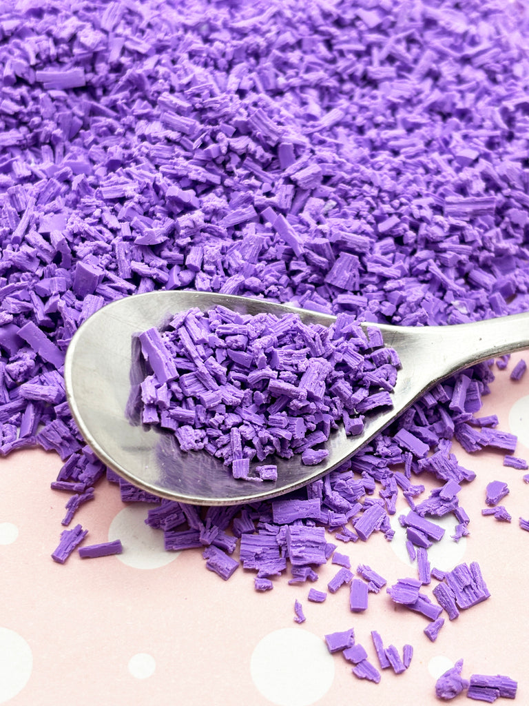 a spoon full of purple colored powder on a table