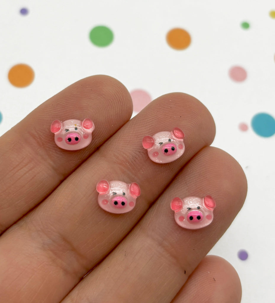 a hand holding a pink pig shaped nail decal