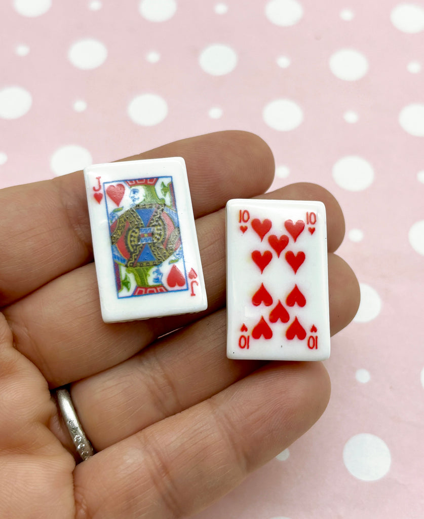 a person holding two small playing cards in their hand
