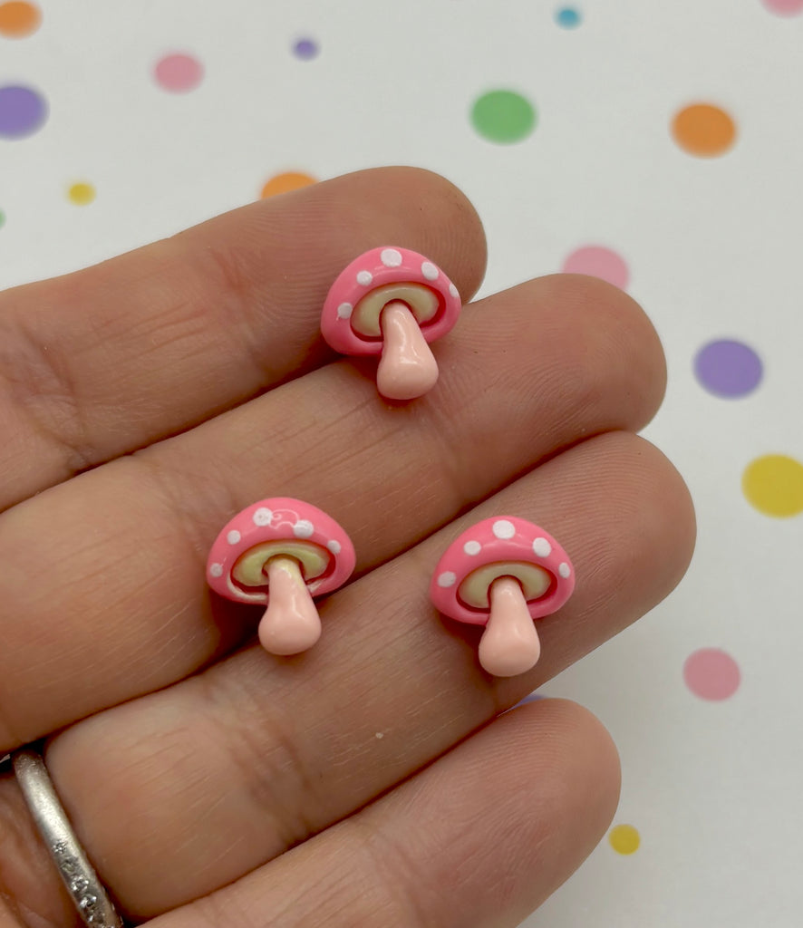 a hand holding a pair of pink and white earrings
