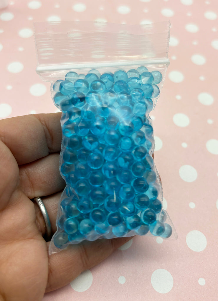 a hand holding a bag of blue beads
