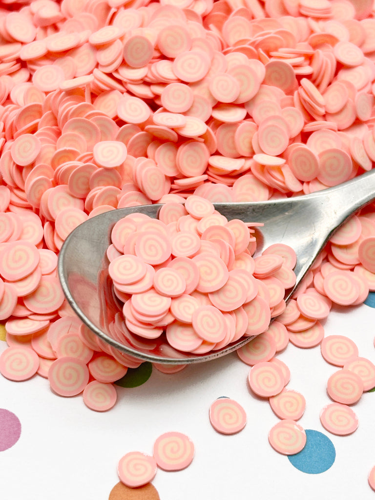 a spoon full of pink candy chips on a table