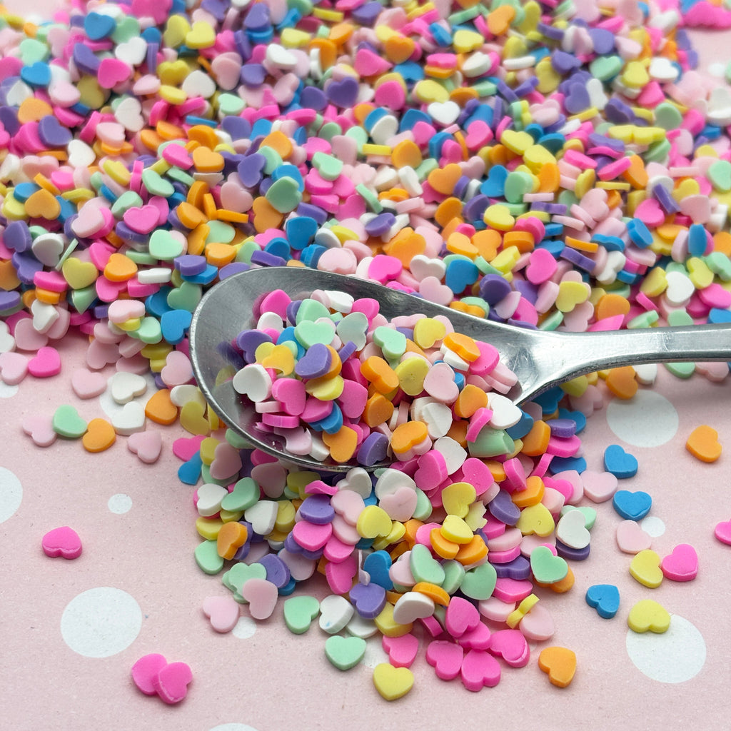 a spoon full of sprinkles on a pink surface