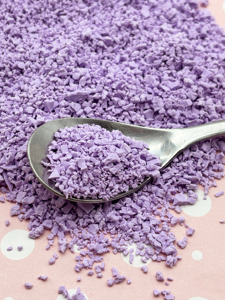 a spoon filled with purple powder on top of a table