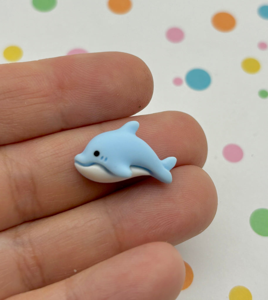 a small blue dolphin toy sitting on top of a person's finger