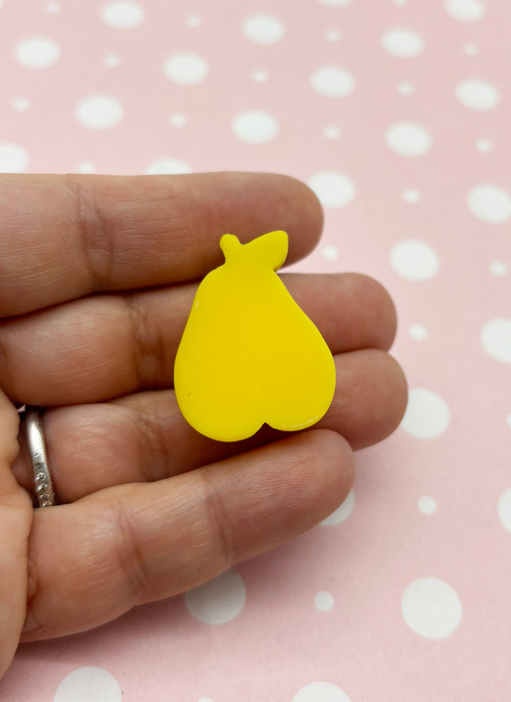 a person is holding a yellow brooch in their hand