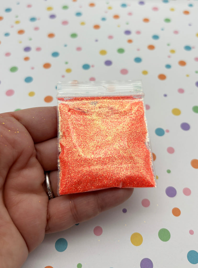a hand holding a small bag of orange glitter