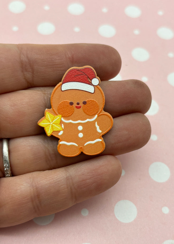 a hand holding a small brown teddy bear wearing a santa hat