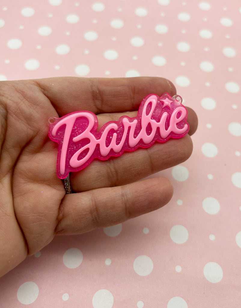 a person is holding a pink barbie keychain