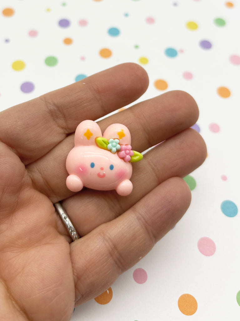 a hand holding a tiny pink pig on it's finger