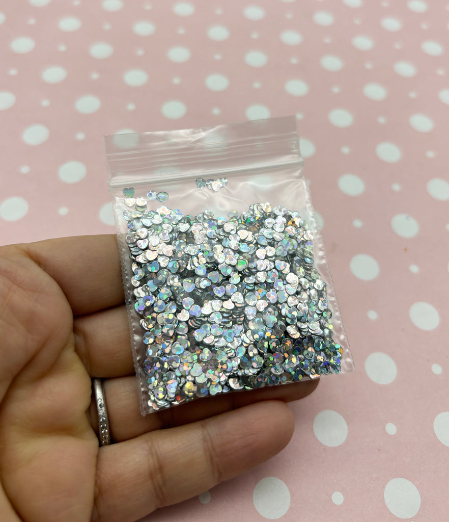 a hand holding a bag of silver glitter