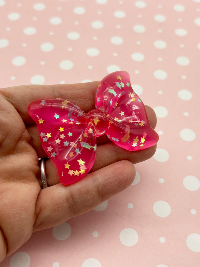 a hand holding a pink bow with stars on it