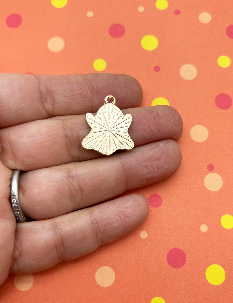 a person holding a tiny gold leaf charm