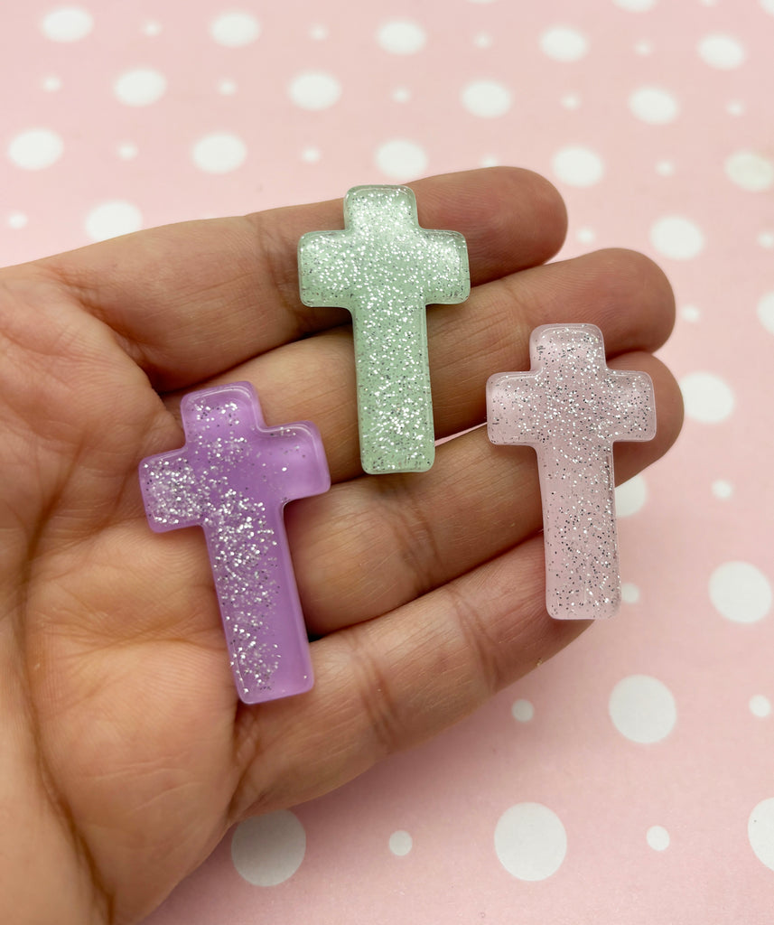 a person holding two small plastic crosses in their hand