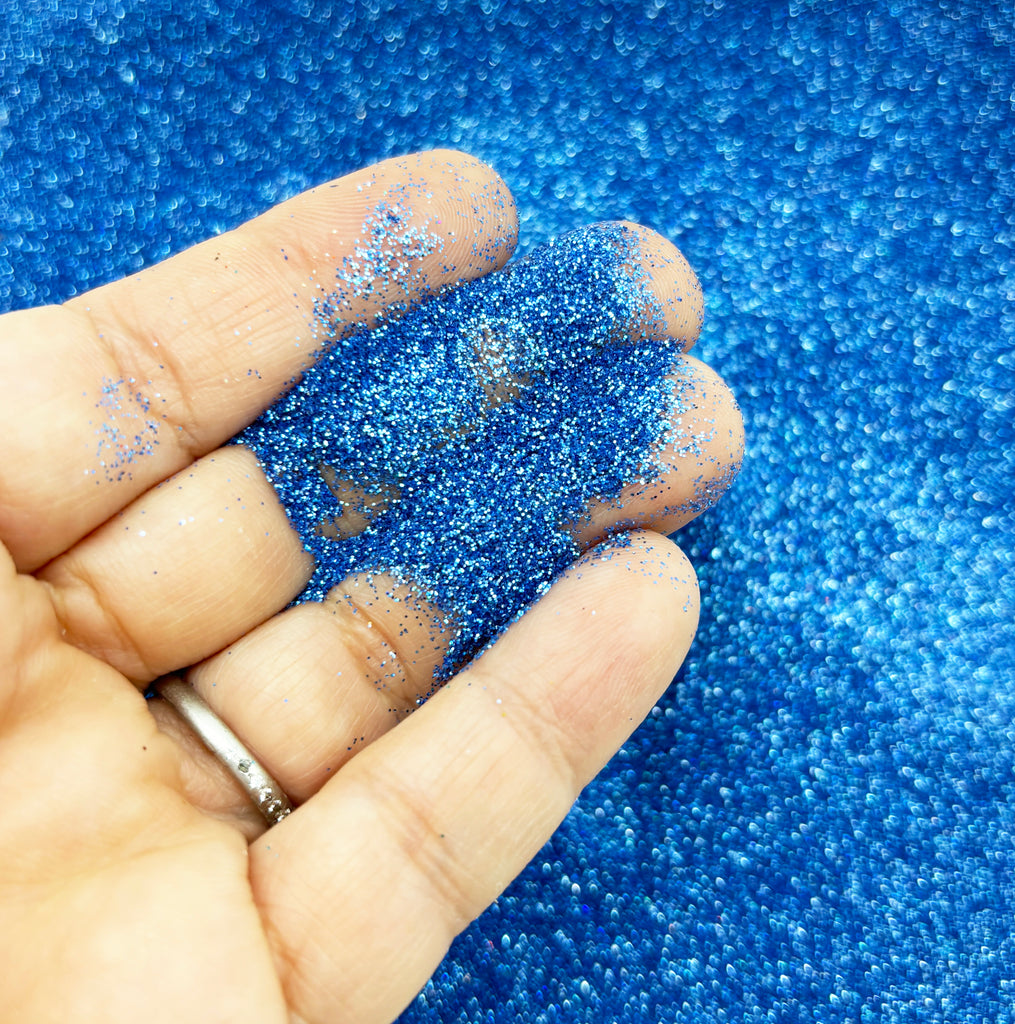a hand holding a piece of blue glitter