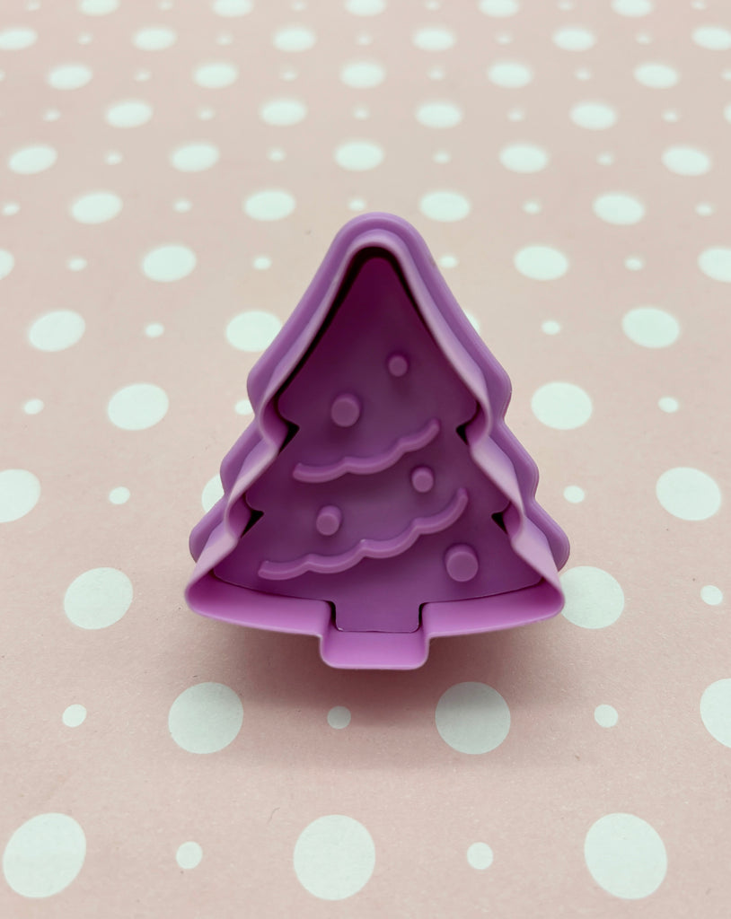 a purple cookie cutter shaped like a christmas tree