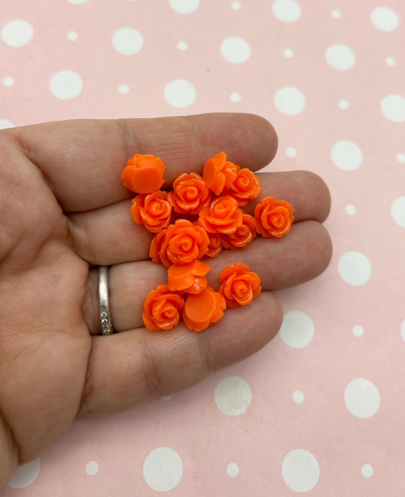 a person's hand holding a bunch of tiny orange flowers
