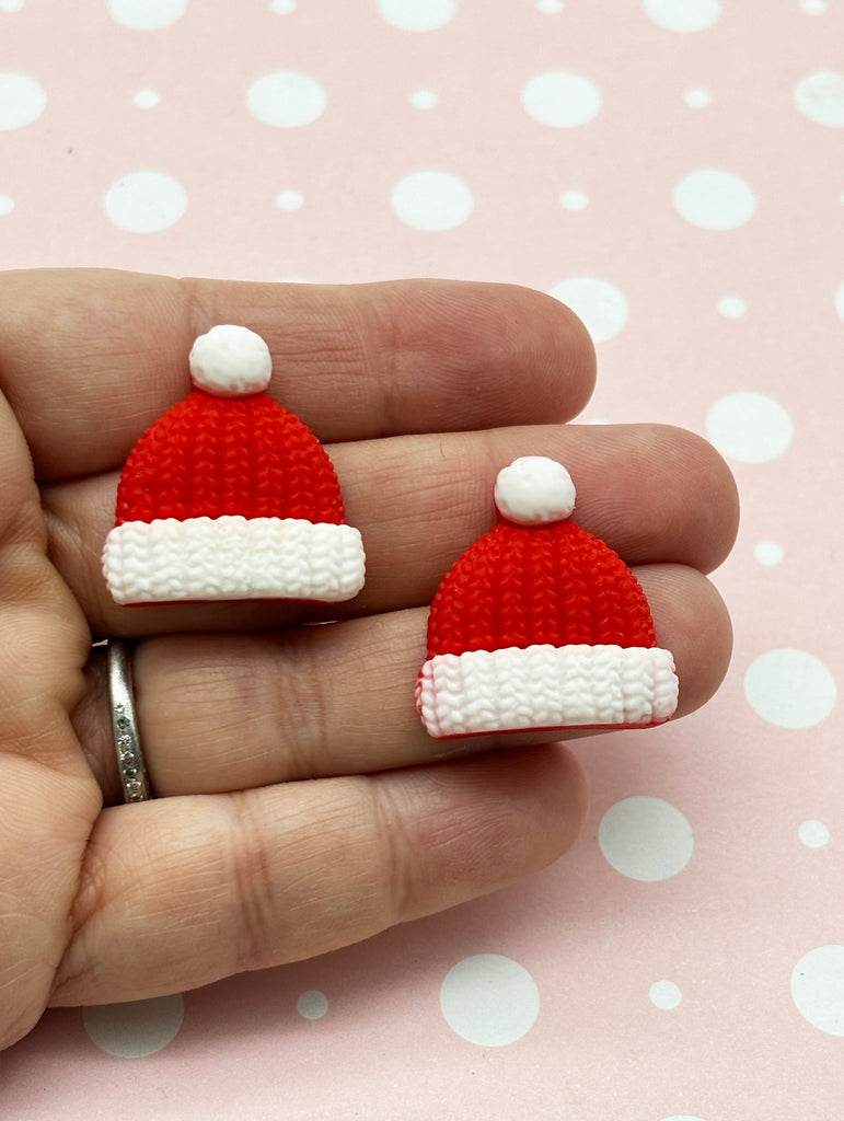 a hand holding a tiny red and white knitted santa hat