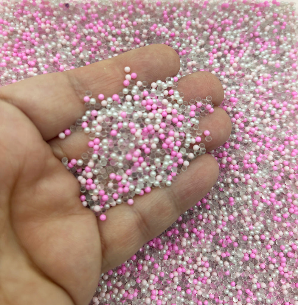 a hand holding a handful of pink and white beads