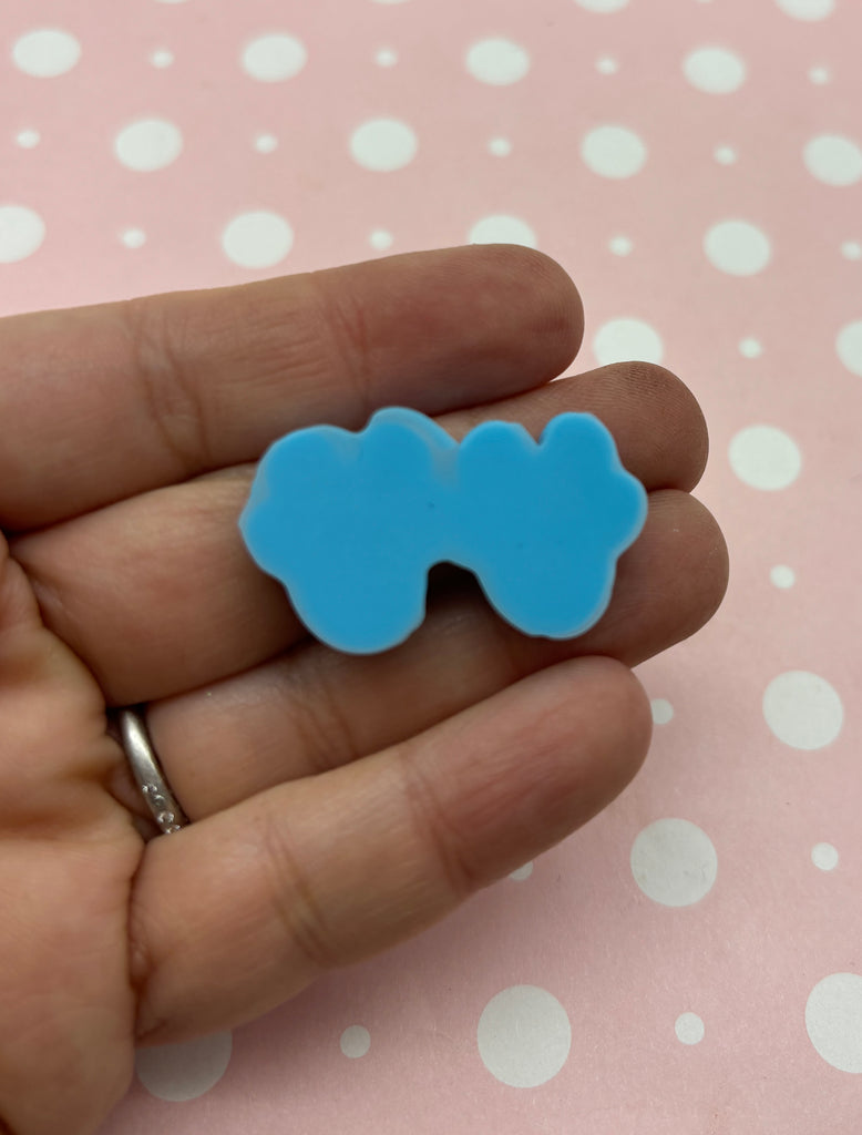 a person is holding a small blue bow brooch