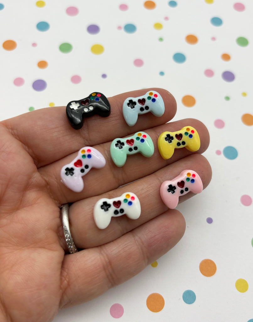 a person's hand with four different colored video game controllers on it