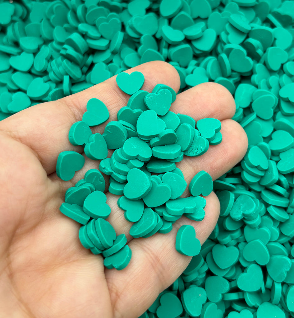 a hand holding a handful of green heart shaped confetti