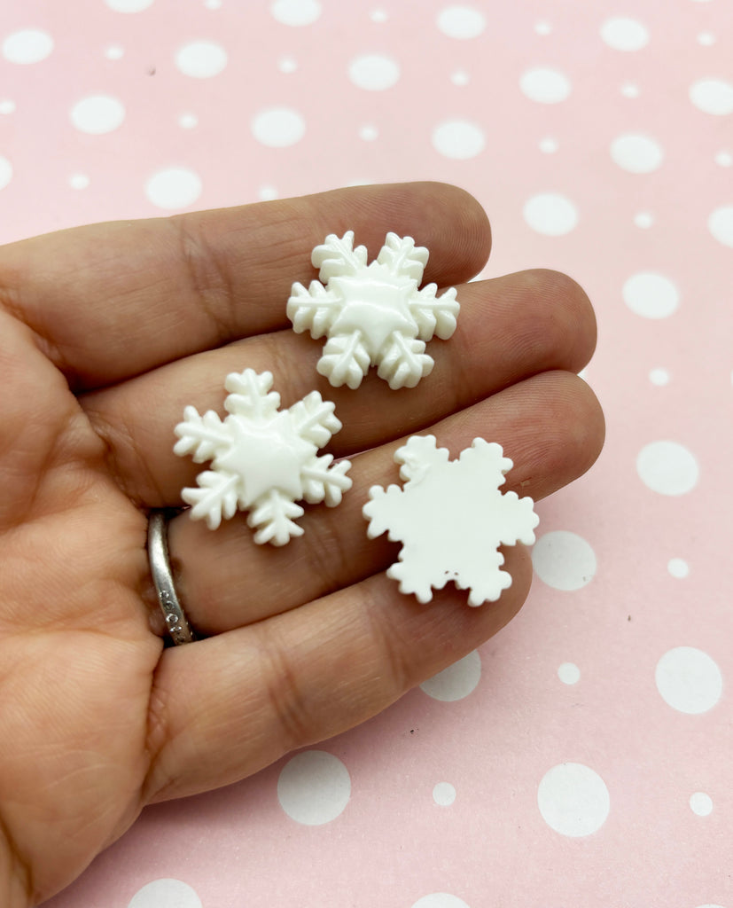 a person's hand holding three small snowflakes