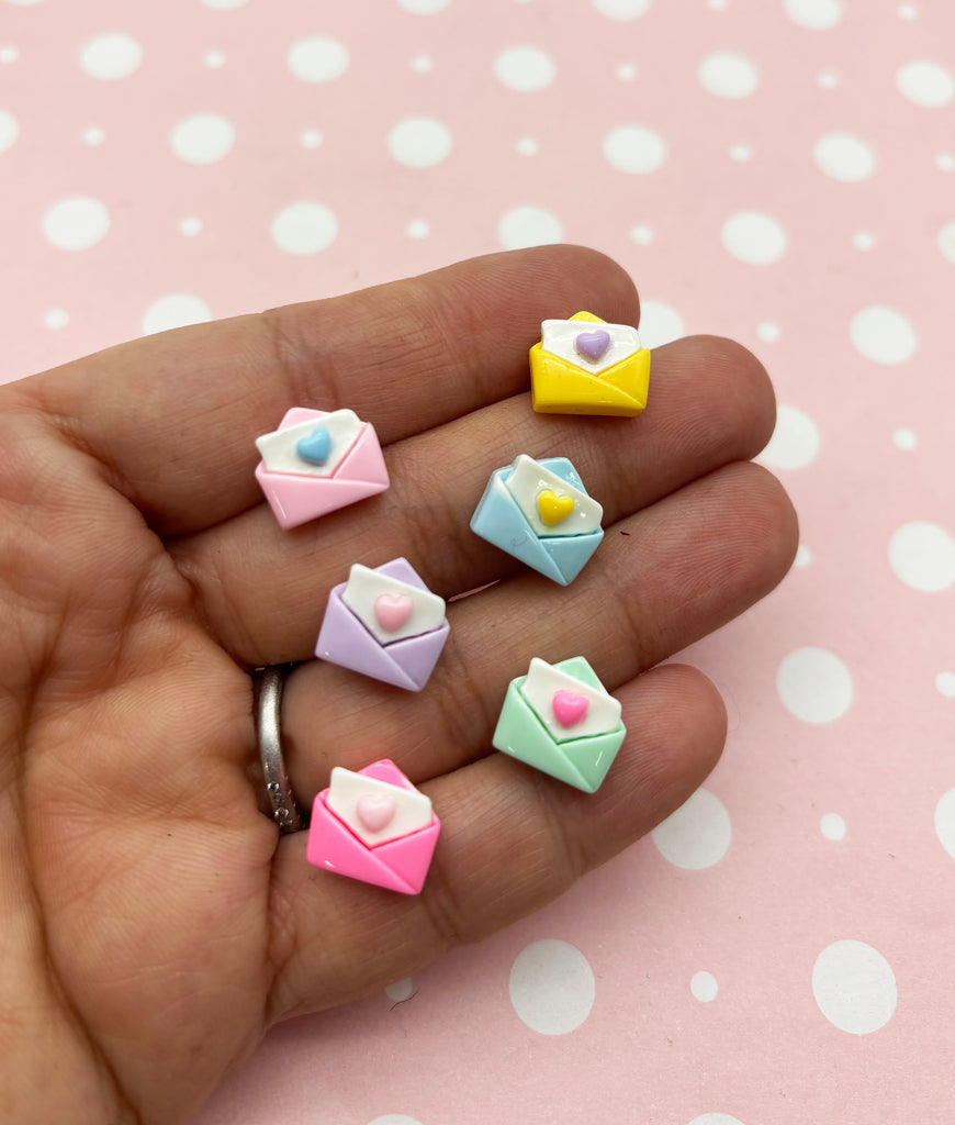 a person's hand holding five small origami envelopes