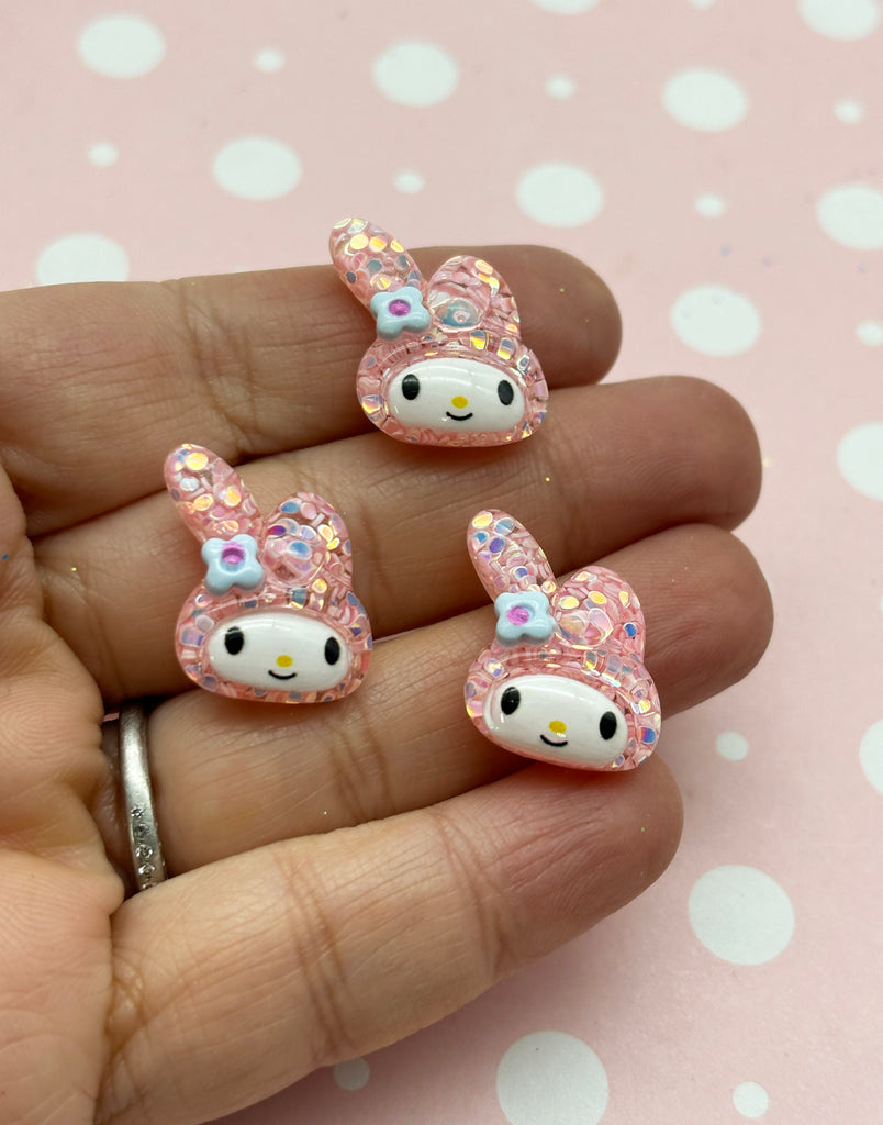 a person is holding three hello kitty earrings