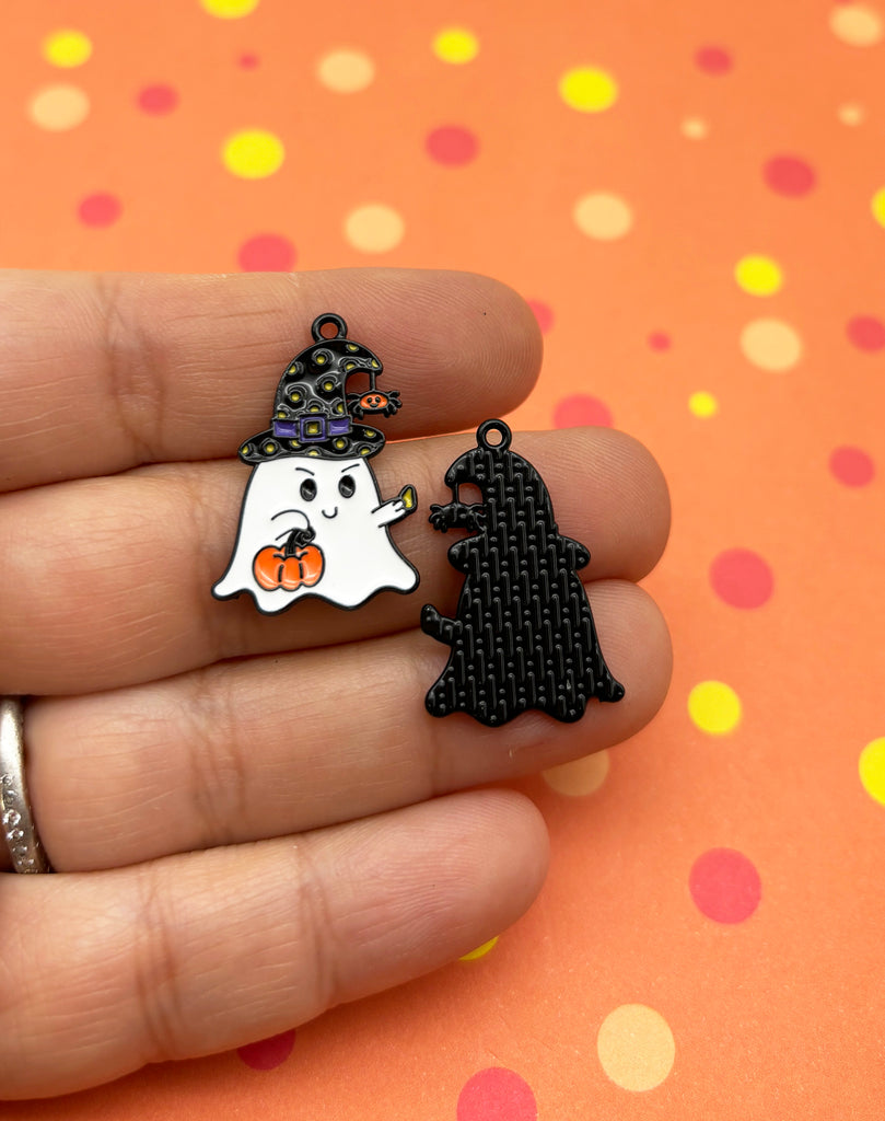a person holding two halloween pins in their hand