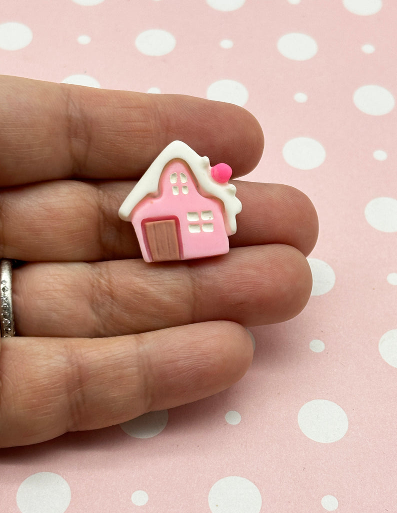 a hand holding a pink house shaped ring