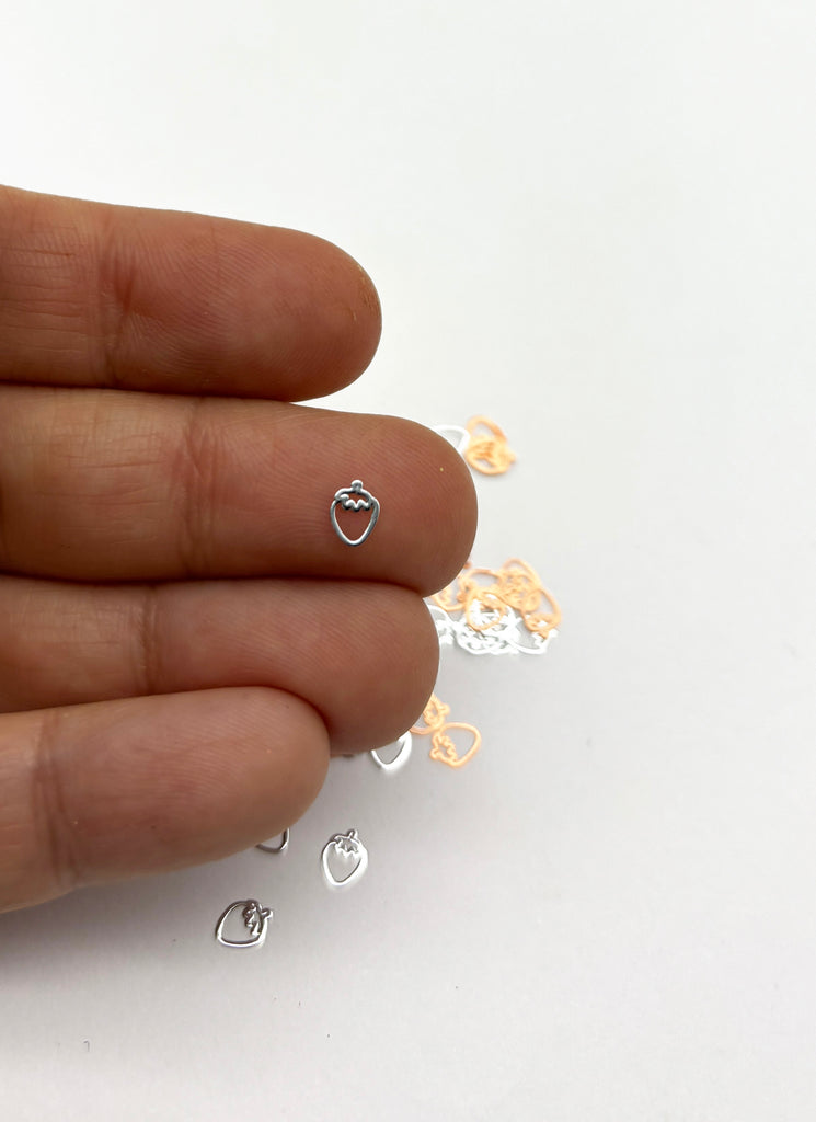 a person's hand holding a tiny heart shaped earring