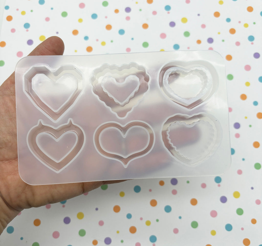 a hand holding a plastic mold with hearts on it