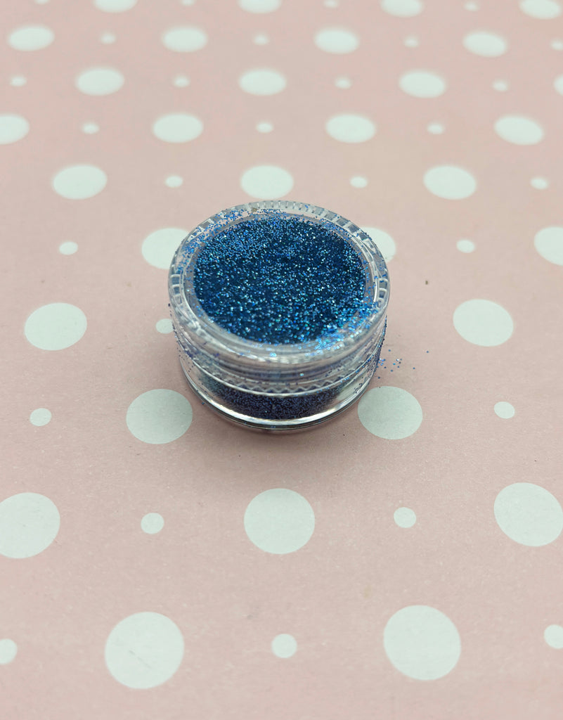 a small jar of blue glitter sitting on top of a polka dot tablecloth