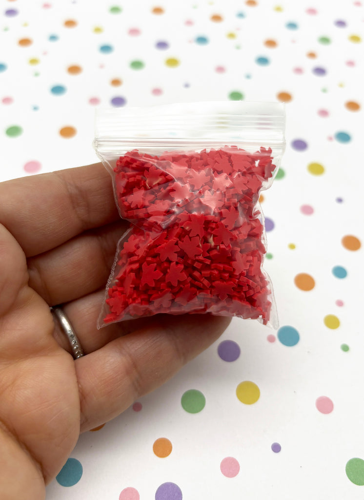 a hand holding a bag of red sprinkles