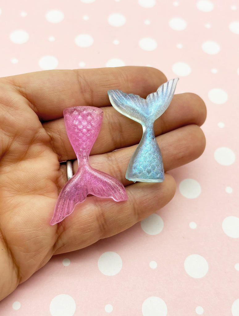 a hand holding two small mermaid tail rings