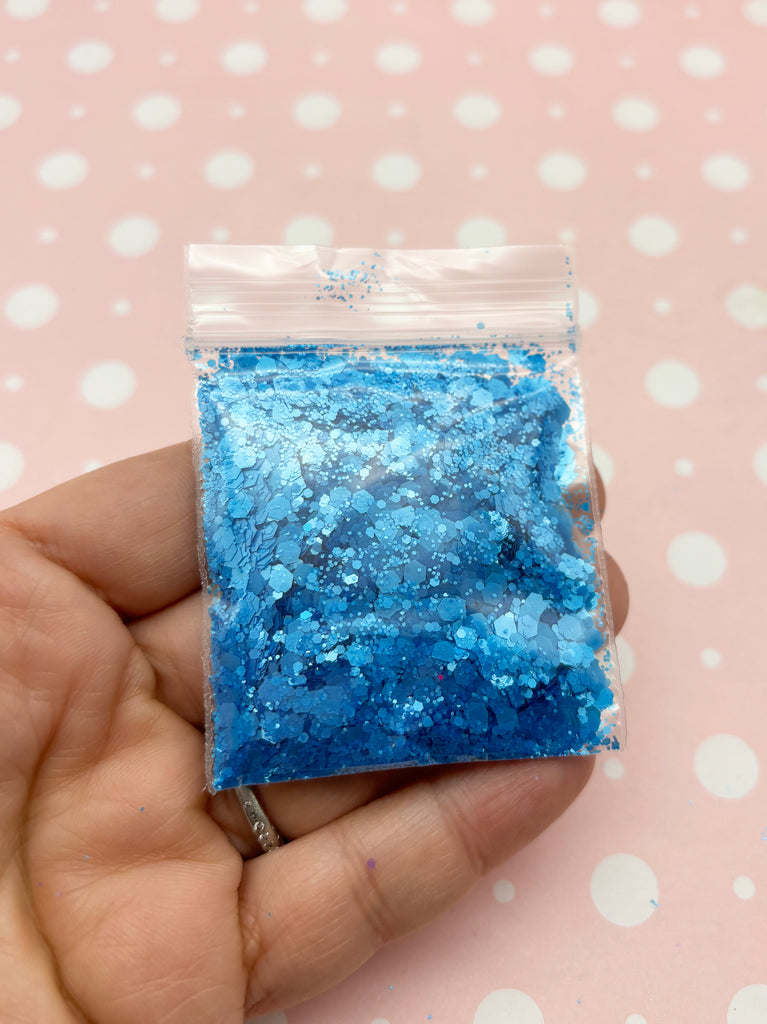 a hand holding a bag of blue glitter
