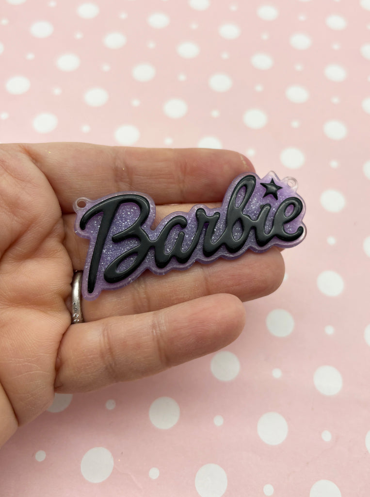 a hand holding a purple and black name pin