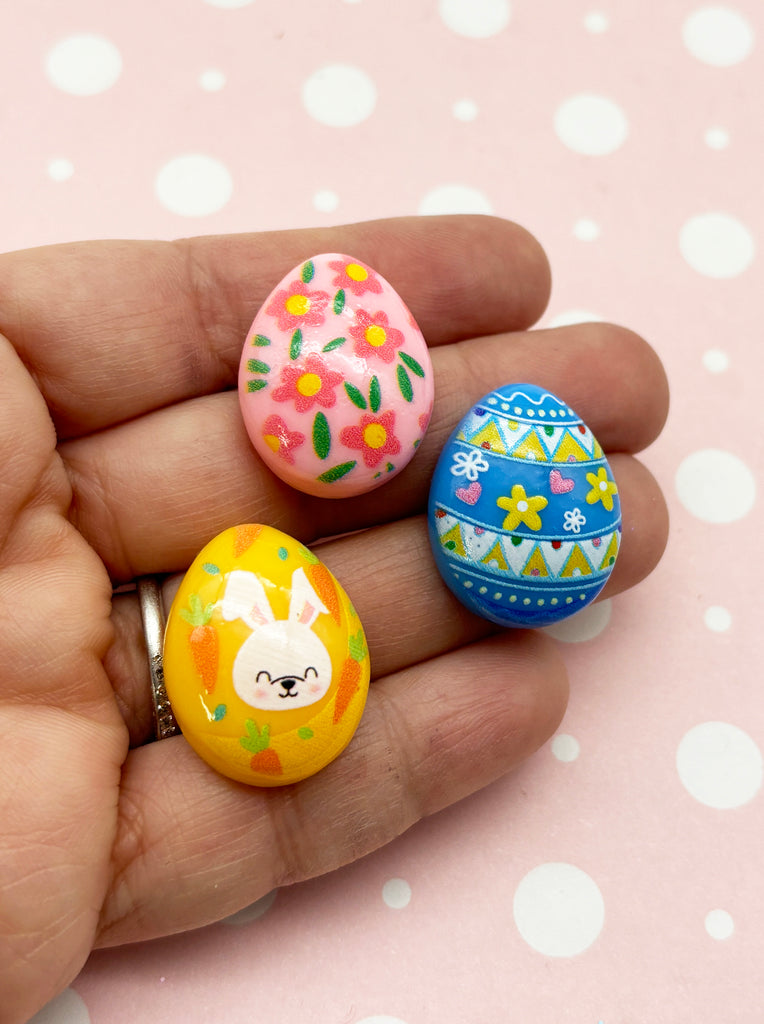 a person is holding three decorated eggs in their hand