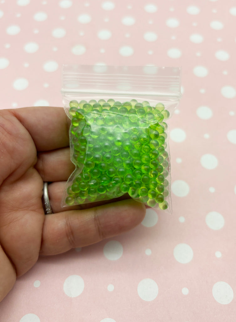 a hand holding a bag of green beads