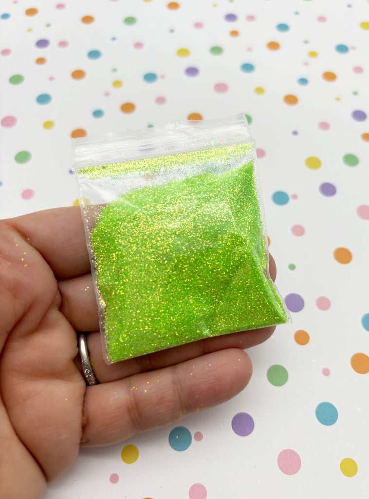 a hand holding a bag of green glitter
