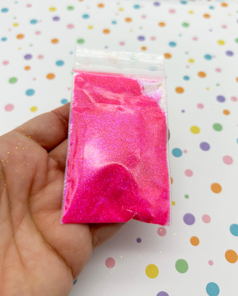 a hand holding a pink bag of glitter