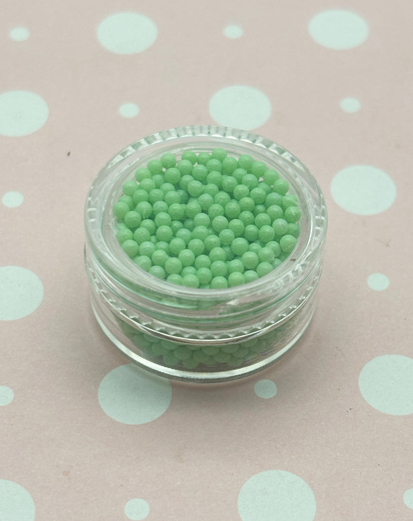 a small glass jar filled with green beads