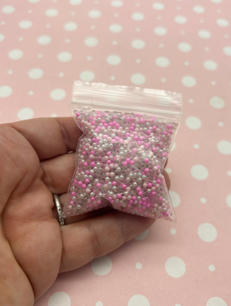 a hand holding a small bag of pink and white sprinkles