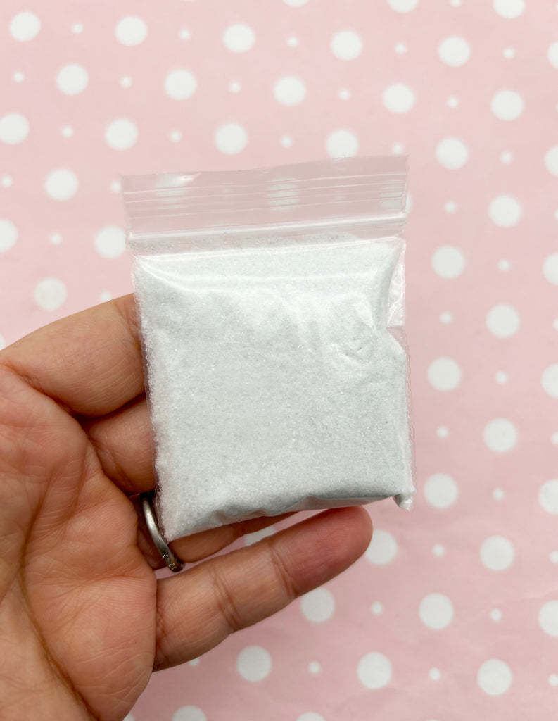 a hand holding a small bag of white powder