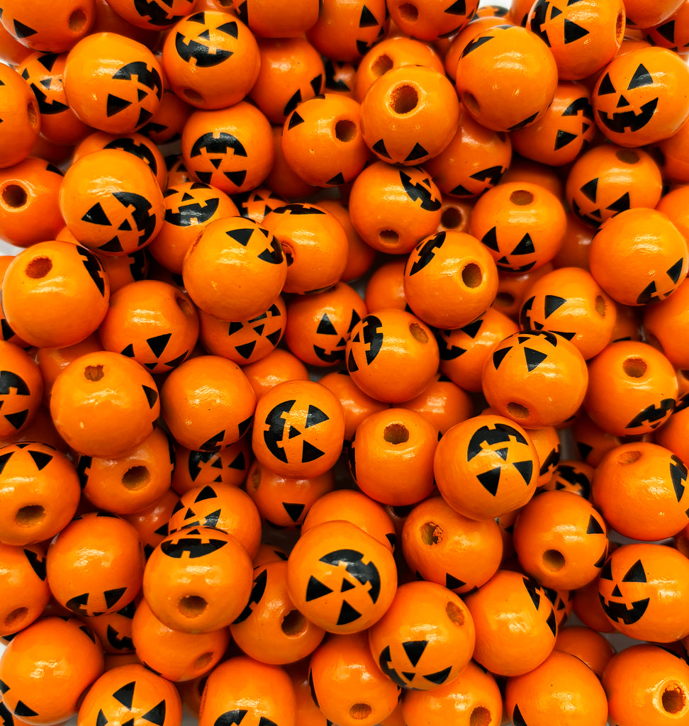 a pile of orange beads with black designs on them